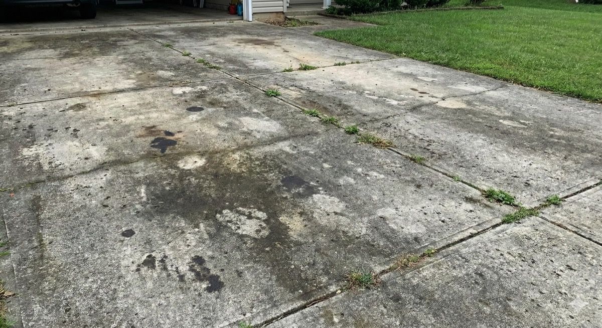 Before: Dirty, stained concrete driveway with weeds in cracks